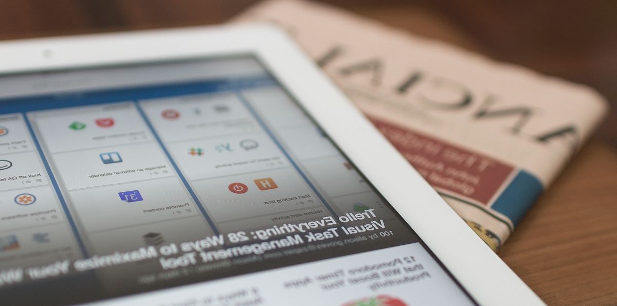 white tablet computer on top of newspaper